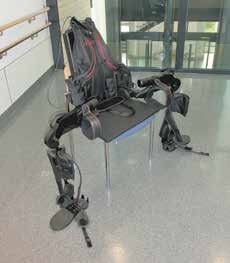 Der Ekso in der Ausgangsposition für den Transfer des Patienten vom Rollstuhl in das Gerät; die „Beine" können nach dem Transfer adduziert werden. Man sieht zusätzlich die gut gepolsterten Schellen zur Fixierung des Patienten sowie die feste Rückenplatte.