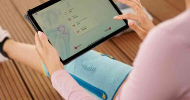Eine Frau trägt eine Bandage und hält ein Tablet auf dem eine Digitale Gesundheitsanwendung (DiGA) geöffnet ist.